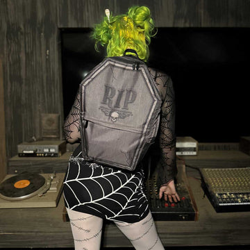 Gothic model is wearing our Gravestone backpack while working DJ equipment.  Model is also wearing a spider-web belt and spider web skirt available in our store