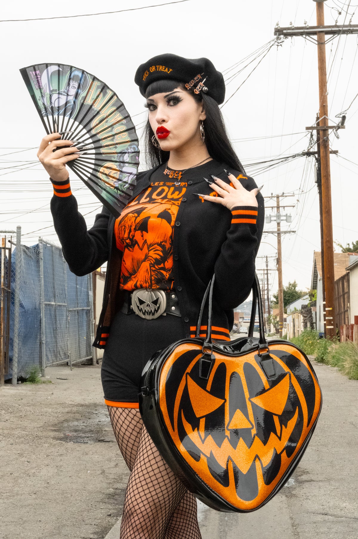 Goth woman wearing the silver-tone pumpkin buckle belt with a black-and-orange outfit, holding a heart-shaped jack-o’-lantern bag