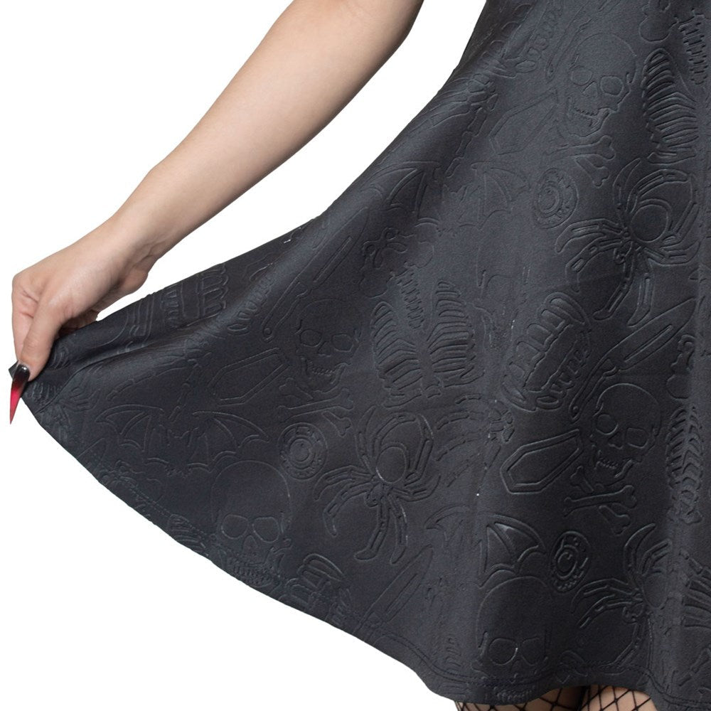 Closeup detail of Black lace dress with spider design held by a hand on a white background